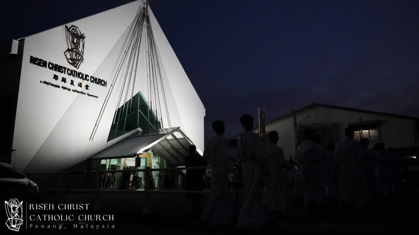The church at dusk: a white, peaked, tent like roof rising above the entrance